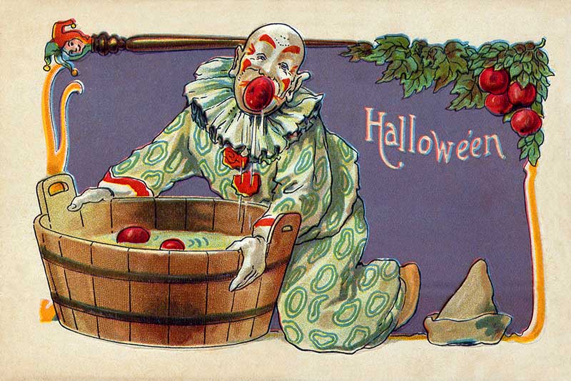 Clown bobbing for apples in a wooden tub Halloween Postcard