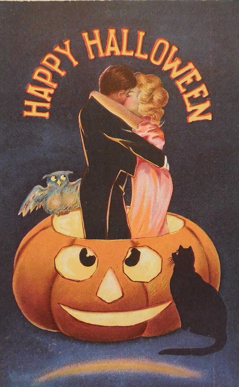 Couple embracing whilst standing in a Jack-o-lantern with onlooking black cat