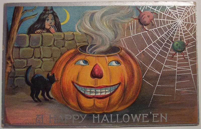 Vintage Happy Halloween postcard with a smiling jack-o’-lantern cauldron, witch behind a wall, black cat and spider web.